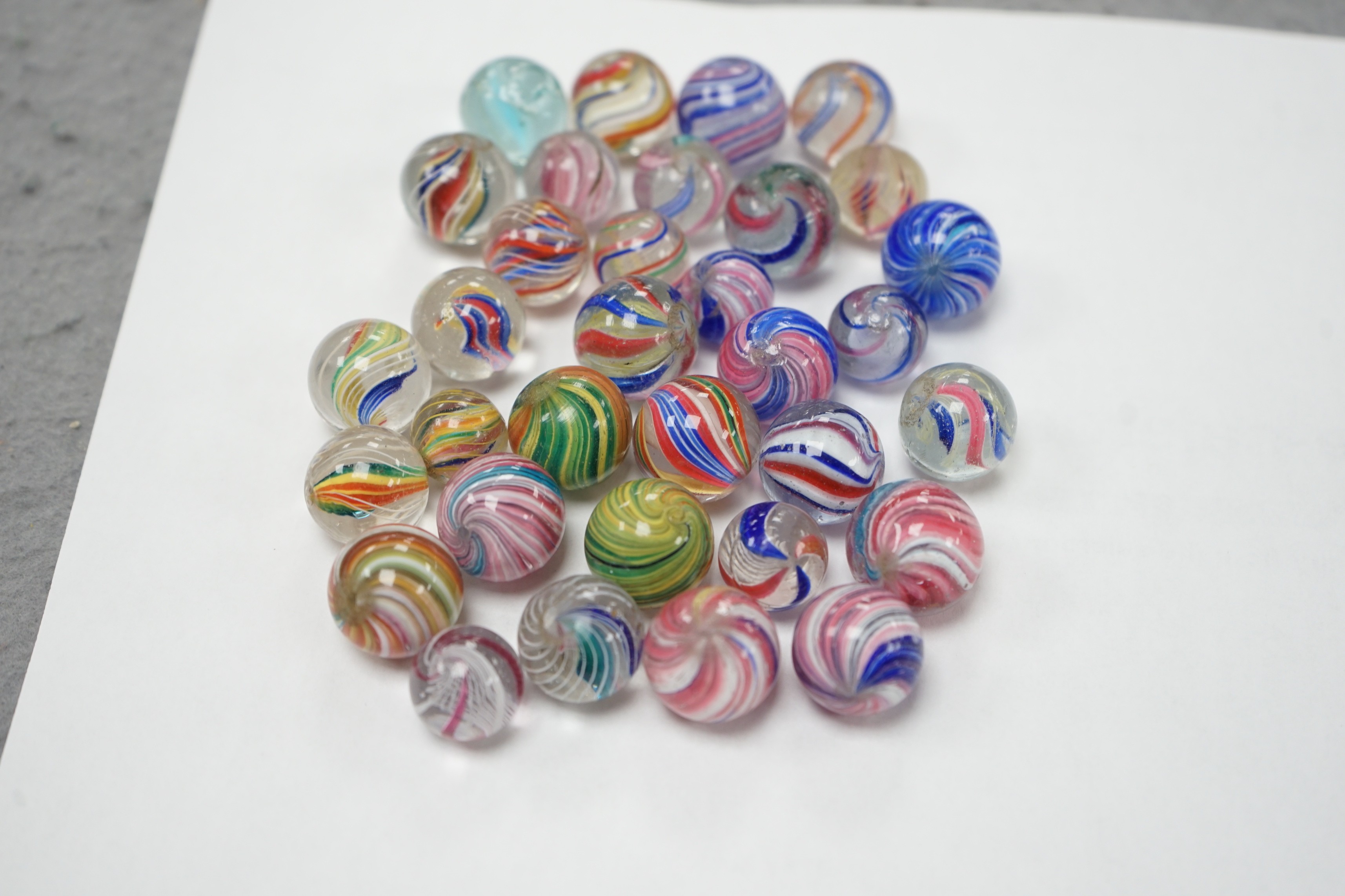 A mahogany solitaire board with a collection of latticino and marbled glass marbles